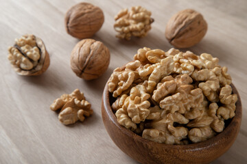 Bowl of walnuts and whole walnut kernels on wooden background,top view	