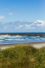 Empty beach with waves crashing and a seawall in distance