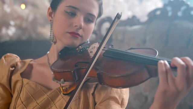 A Young Girl And Man Plays The Violin In A Beautiful Retro Room With Flowers And A Piano.