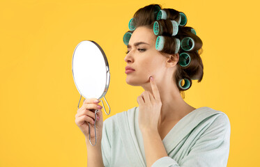 Lady Touching Face Having Pimples Looking In Mirror, Yellow Background