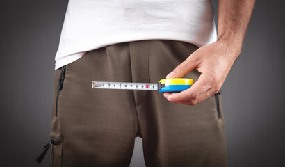 Man with a measuring tape measures his penis size.