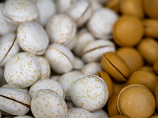 Assortment of mini macaron sweet confections. White vanilla macaroon with sugar sprinkles and coffee flavor. Cookie sandwiches delicatessen for dessert.