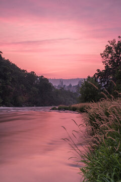 Pink sunset sky over whitewater river and forest