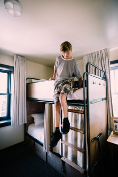 Teen Boy Slides down From Bunkbed in Hostel