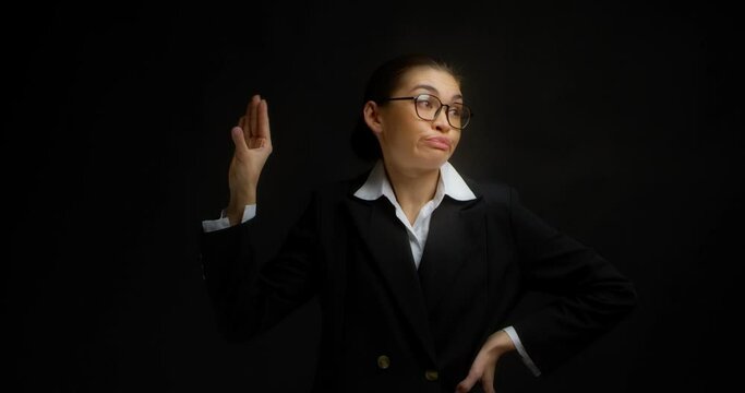 Horizontal shot of a business woman in glasses and office clothes, tired of the conversation of the interlocutor. Beautiful brunette shows her left hand gesture blah, blah, blah.On a black background