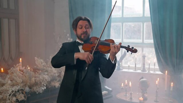 A Young Girl And Man Plays The Violin In A Beautiful Retro Room With Flowers And A Piano.