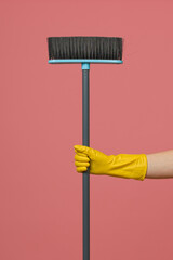 a hand in a yellow rubber glove holds a brush on a colored background