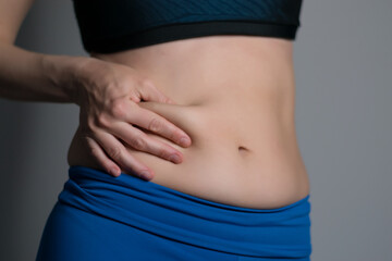 Woman holding and pushing the skin of the stomack cellulite.