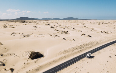 Modern camper van outdoor parking with sand desert view landscape. Concept of travel and adventure...