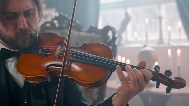 A Young Girl And Man Plays The Violin In A Beautiful Retro Room With Flowers And A Piano.