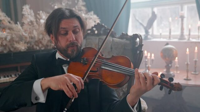 A Young Girl And Man Plays The Violin In A Beautiful Retro Room With Flowers And A Piano.