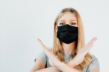 Good-looking young woman is wearing a face mask and standing with crossed hands. The girl is...