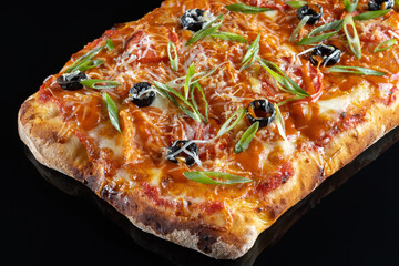 Pizza with cheese, olives and green onions. On a black isolated background.