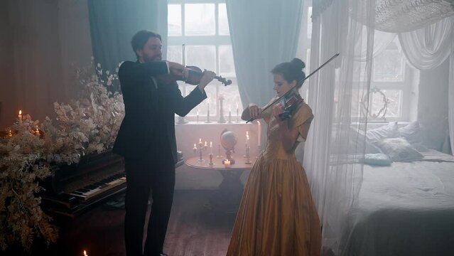 A Young Girl And Man Plays The Violin In A Beautiful Retro Room With Flowers And A Piano.