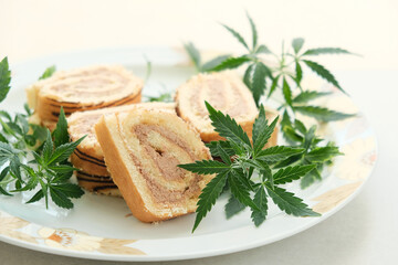 Sweet roll with marijuana oil on white plate. Cannabis kitchen. Layout of delicious dessert, top view close up.