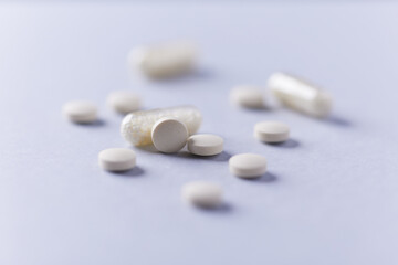 Vitamin C tablets and capsules on bright paper background. Close up. Copy space. 