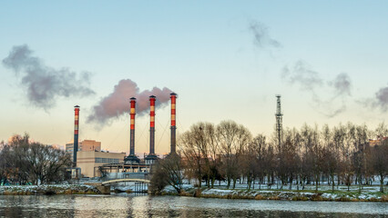 Obraz premium Power station with reservoir in winter. Beautiful seaside winter sunset with a smoking factory chimney.