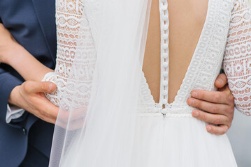 Beautiful bridesmaid dress back with numerous buttons. The groom embraces the bride's waist, close-up