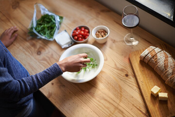 Making a healthy snack. A young woman making a salad in her kitchen.