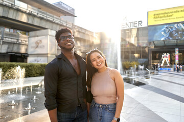 Portrait of two multiracial friends smiling and stanging on a mall