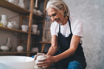 Female sculptor making clay pot on pottery wheel