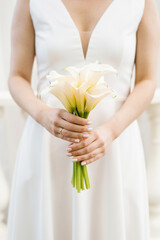 White bridal bouquet of calla lilies in the hands of the bride