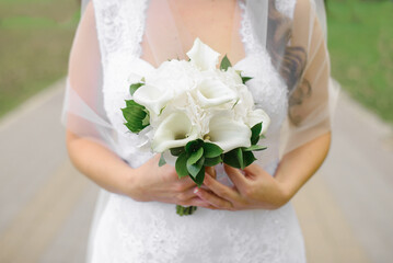 Bridal bouquet of white calla lilies in the hands of the bride close-up