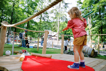 Cute preschool girl playing mini golf with family. Happy toddler child having fun with outdoor activity. Summer sport for children and adults, outdoors. Family vacations or resort. - obrazy, fototapety, plakaty