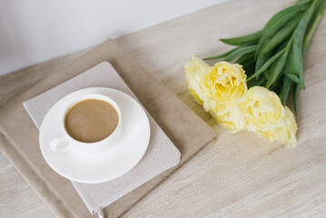 Creative composition of beautiful delicate yellow tulips, notebooks and a cup of coffee on the desktop of a freelancer or blogger