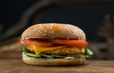 Burger with cutlet and tomato. Photo of food on a dark background