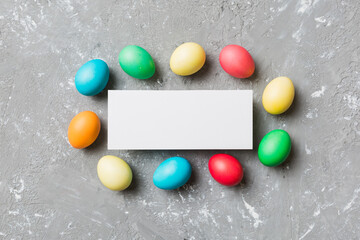 round frame multicolored Easter eggs with white blank paper on a brown background, close-up, space for text, blank for design, selective focus, tinted image
