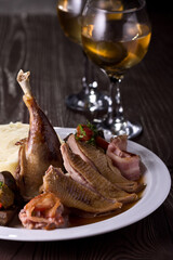 Roast duck on a plate, in a glass of whiskey. Photo of food on a dark background