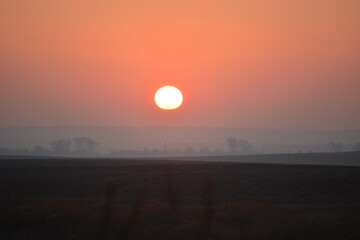Obraz premium Sun fireball hanging in the fog over a grass field in the countryside