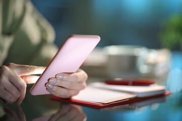 Close up of a woman hand using phone beside agenda