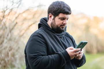 Obese man checks mobile phone
