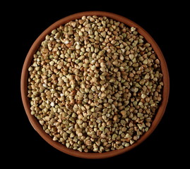 Buckwheat green seed pile in clay pot, bowl isolated on black, top  