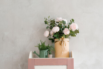 Artificial pink roses in a vase, in a watering can, as a decor for a children's room