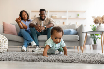 Fototapeta premium Cute baby toddler walking in living room making first steps
