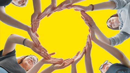 Friends make a circle with their palms against a yellow background.