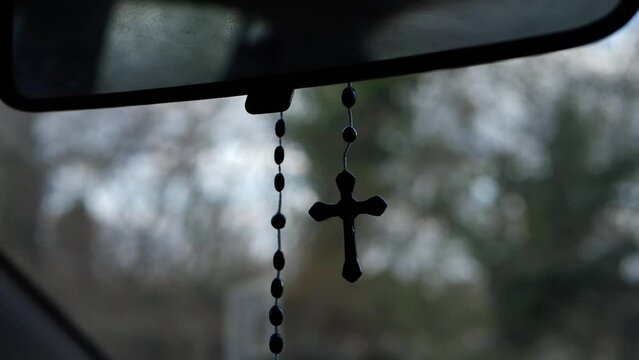 Rosary beads crucifix hangs on windscreen rear mirror