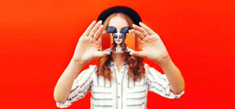 Close up of modern young woman stretching her hands taking selfie picture by smartphone on red background
