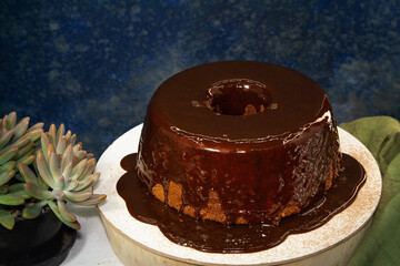 Homemade chocolate cake with syrup poured on top. Dark mottled blue background in the background. Space for art.