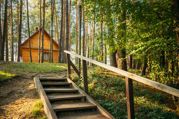 Tourist Guest House For Rest. Wooden House In Forest In Autumn Sunny Day. Wooden Boarding Path Way Pathway Leading To Tourist House. Resort In Wooden Guest House.
