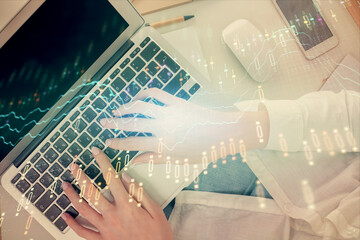 Double exposure of woman hands working on computer and forex chart hologram drawing. Top View....