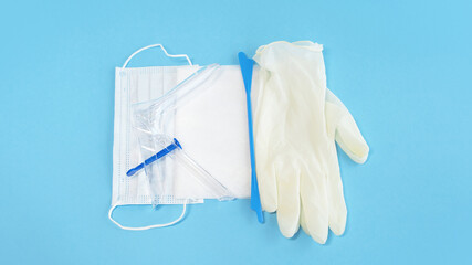 Basic set for vaginal examination on blue background. Gynecological speculum, gloves, spatula,...
