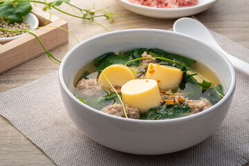 Clear Ivy gourd soup with minced pork and egg tofu in white bowl on wooden table,Thai food.(gaeng jued tum luang)