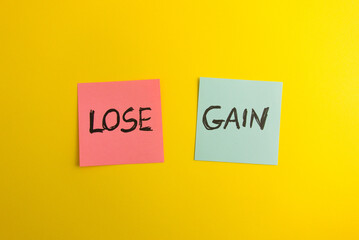 Words lose and gain handwritten on colorful sticky notes