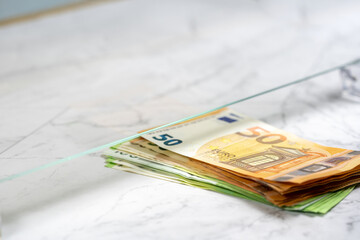 Person pay money to teller at cash department window, closeup. Exchange a 50 and 100 euro notes to buy and sell.