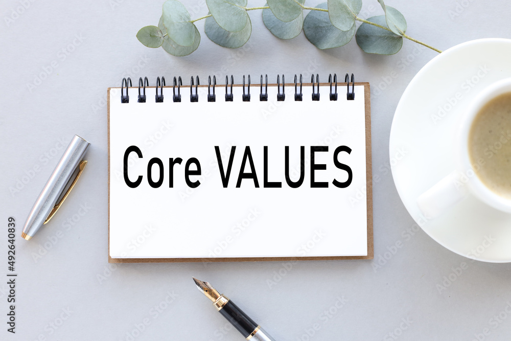 Poster core values text on an open notebook near a cup of coffee