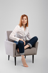 Middle age woman sitting in armchair and looking tense